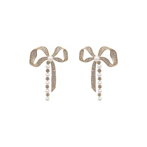 Elegant gold bow earrings featuring sparkling rhinestones and dangling white pearls