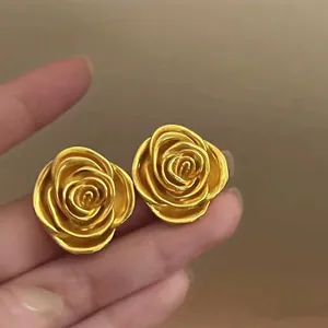 Detailed macro view of elegant gold rose flower earrings with textured layered petals