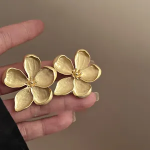 Detailed macro view of matte gold flower stud earrings featuring elegant wrinkled petal texture