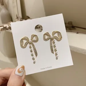 Detailed shot of elegant gold bow-knot earrings featuring sparkling crystals and pearls.