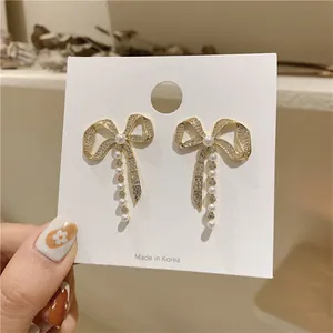 Close-up of elegant gold bow earrings with sparkling rhinestones and dangling pearls