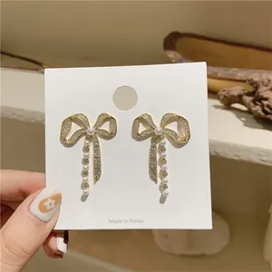 Detailed macro view of elegant gold bowknot earrings with rhinestones and white pearls
