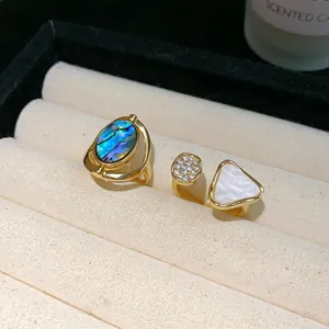 Makro-Detail eines goldenen offenen Rings mit weißem Perlmutt-Dreieck und Zirkon-Pavé