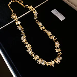 Detailed close-up view of a gold-plated necklace with irregular square frames and zircons