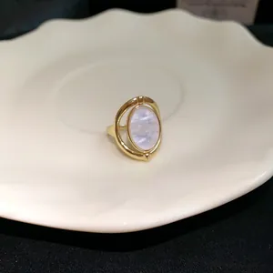 Detailansicht eines goldenen verstellbaren Rings mit ovalem Perlmutt-Stein