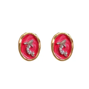 Vintage oval goldfish earrings with red enamel and pearl accents on a white background.