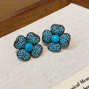 Detailed close-up of vintage flower-shaped stud earrings with turquoise-colored beads