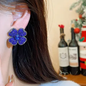 Close-up detail of exquisite vintage blue rhinestone clover earrings worn on a female ear