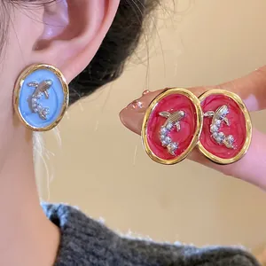 Macro view of vintage oval goldfish earrings with pearls in blue and red enamel