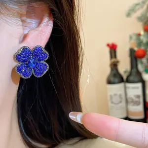 Macro view of an elegant blue crystal flower earring worn on ear with festive background