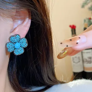 Close-up detail of a vintage-style blue flower stud earring with unique textured finish