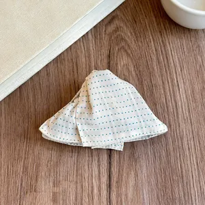 Detailed view of a triangular fabric hair claw clip with blue polka dots on wood