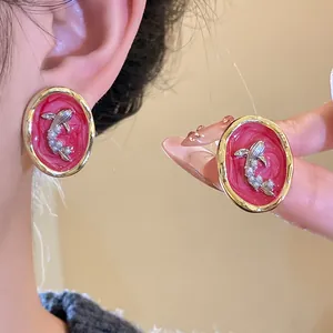 Close-up detail of vintage oval goldfish earrings featuring pearls and red resin