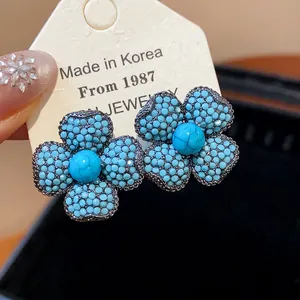 Detailed macro view of elegant blue flower earrings with textured turquoise beads