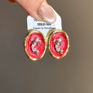 Detailed close-up view of vintage oval gold earrings featuring koi fish and pearl accents