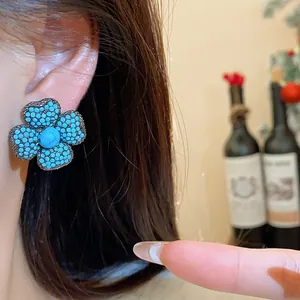 Detailed view of vintage silver needle flower earrings inlaid with turquoise-colored micro beads