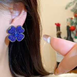 Detailed macro view of an elegant blue rhinestone flower earring on a woman's ear.