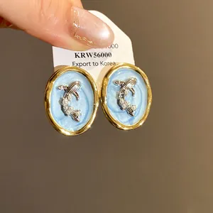 Detailed view of vintage gold-rimmed oval goldfish earrings with delicate pearls and blue center