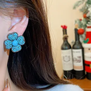 Close-up detail of vintage style flower earrings with turquoise beads and silver needle.