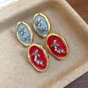 Detailed view of vintage oval goldfish earrings with pearls in red and blue enamel.