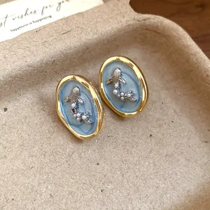 Close-up of vintage oval goldfish earrings with pearl accents and blue enamel detail