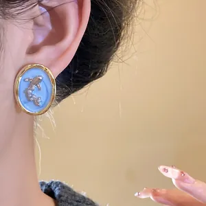 Macro detail of vintage oval goldfish stud earrings with pearls worn by a model