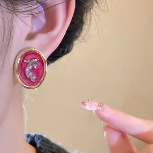 Detailed macro shot of vintage oval goldfish stud earring with pearls and red background