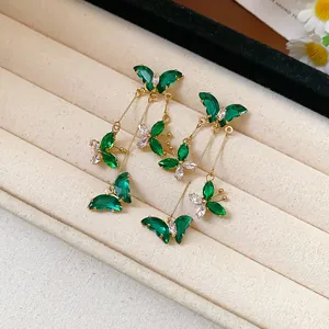 Detailed view of green zircon butterfly tassel earrings on a velvet jewelry tray.