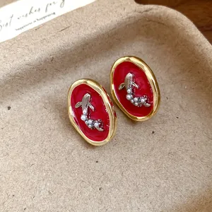 Close-up detail of vintage oval goldfish pearl earrings with a red enamel inlay