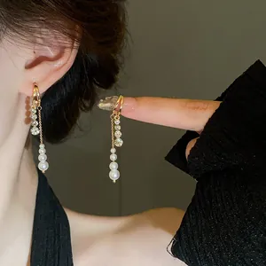 Detailed macro shot of elegant pearl and crystal tassel earrings worn on a model