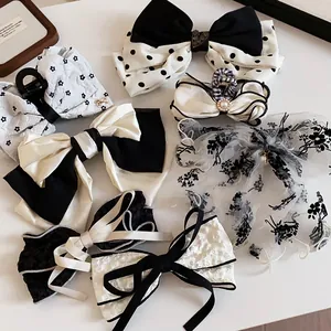 Elegant collection of black and white fabric hair bows and clips in various patterns.