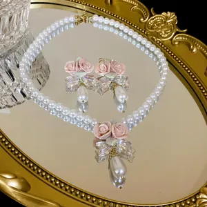 Detail view of pearl necklace and earring set with pink ceramic roses on gold mirror