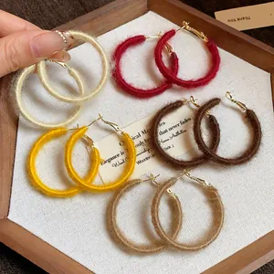 Detailed macro view of colorful autumn fabric-wrapped hoop earrings in a wooden display tray