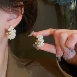Close-up of elegant French vintage style cluster pearl earrings on ear and hand.