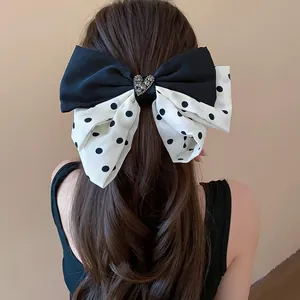 Elegant large fabric bow hair clip with heart rhinestone and black polka dots on model