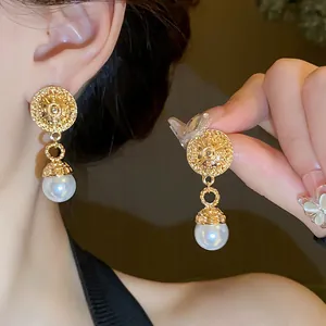 Detailed view of French vintage pearl drop earrings featuring textured gold finish