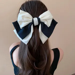 Close-up of a large black and white fabric bow hair clip worn on a model back view