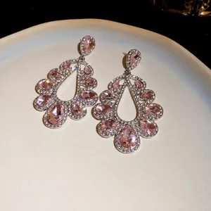 Eleganti orecchini a goccia con cristalli rosa e strass su un piatto in ceramica color crema