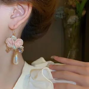 Detailed view of handmade pink ceramic rose earrings with elegant teardrop pearl and gold hook