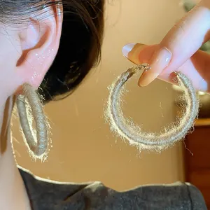 Close-up of fabric woven hoop earrings showing textured fuzzy detail and ear wear