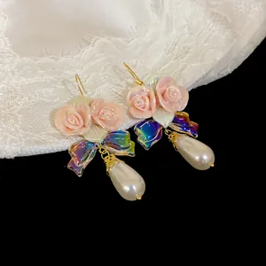 Close-up of pink ceramic flower earrings with teardrop pearls and iridescent bows