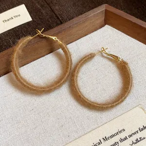 Close-up of brown fabric woven hoop earrings with a cozy fuzzy yarn texture for winter