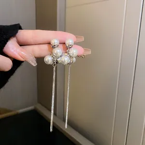 Close-up of vintage-style silver earrings with white pearls and long chain tassels