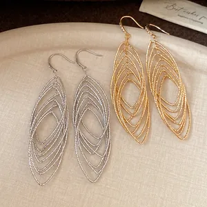 Close-up of retro gold and silver oval hollow layered dangle earrings with zircon detail