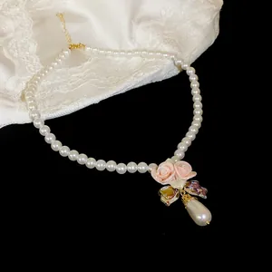 Close-up of pearl necklace featuring pink ceramic roses and an iridescent drop pearl