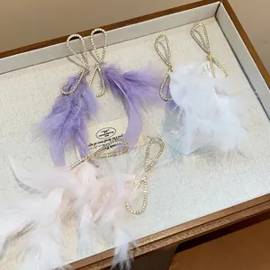 Primo piano di orecchini con nappe di piume e strass in viola, bianco e rosa per donna.