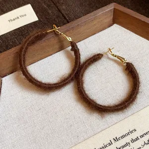 Detailed macro shot of brown fuzzy fabric woven hoop earrings for winter fashion style
