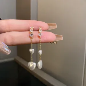 Detailed view of elegant gold tassel earrings with two romantic heart-shaped pearls