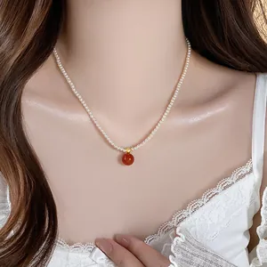 Elegante französische Vintage-Perlenkette mit roter Achatperle am Hals eines Models