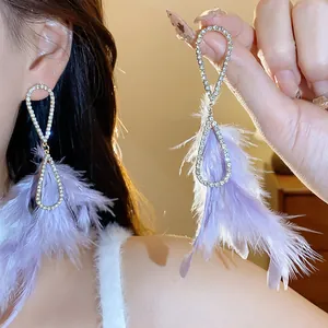 Dettaglio di eleganti orecchini a nappa con piume viola e cornice di strass brillanti